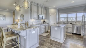 A spacious kitchen with marble countertops, white cabinetry, and stainless steel appliances. - Blessed at the Beach - Gulf View, Heated Pool and Jacuzzi. (Dauphin Island)