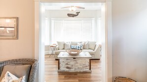 A living room with a white sofa, a coffee table, and a ceiling fan.