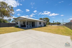 Une maison de plain-pied dotée d’un patio couvert, d’un espace barbecue et d’une cour clôturée.