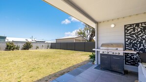 A backyard with a barbecue grill, a covered patio, and a view of neighboring buildings. - Seagulls is the ultimate seaside escape! (Lancelin)
