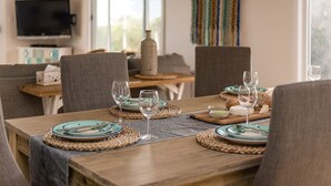 A dining area with a wooden table set for four, surrounded by grey upholstered chairs. - Private Luxury Couples Retreat The Bathhouse at Aldinga Bay. Sunsets, BeachWalks (Sellicks Beach)