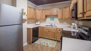 A compact kitchen with wooden cabinets, a stainless steel refrigerator, a dishwasher, a coffee maker, and a microwave. - Comfy and Cozy 5 min walk to the Gulf in Historic District (Gulfport)