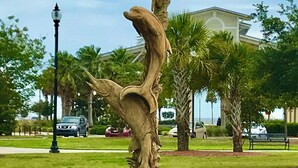 A sculpture of a tree with a bird perched on it, located in a grassy area with a building in the background. - Comfy and Cozy 5 min walk to the Gulf in Historic District (Gulfport)