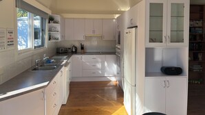 Una cocina moderna con armarios blancos, horno empotrado, refrigerador con puertas de vidrio y ventana con vista al exterior.