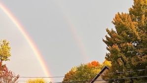 A residential area with houses, a visible rainbow, and autumn-colored trees. - Idyllic Location - Walk to Town and Beaches (South Haven)