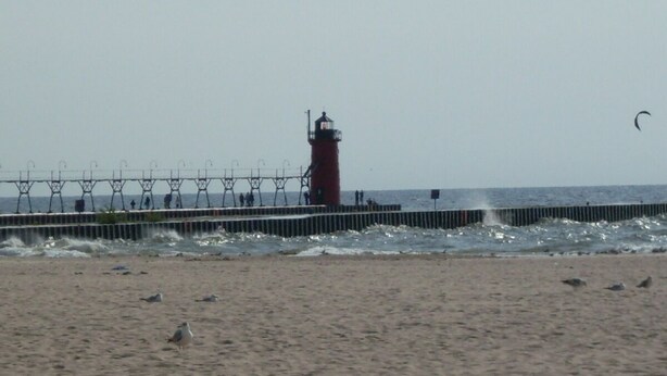 A lighthouse on a pier with waves crashing against it. - Idyllic Location - Walk to Town and Beaches (South Haven)
