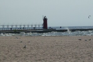 A lighthouse on a pier with waves crashing against it. - Idyllic Location - Walk to Town and Beaches (South Haven)