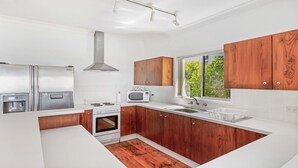 A modern kitchen with white cabinetry, stainless steel appliances, and a wooden floor.