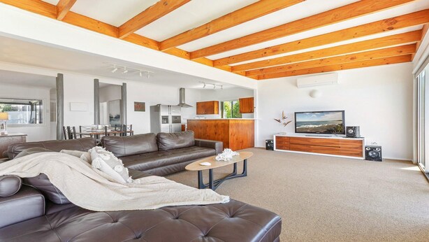 A modern living room with a leather sofa, a coffee table, and a TV on a wooden cabinet.