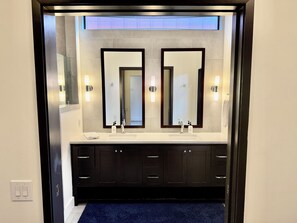 Une salle de bain moderne avec deux vasques, des meubles de couleur sombre et un grand miroir.