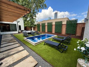 Un jardin avec une piscine, des chaises longues et une pergola.