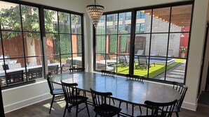 Een eethoek met een grote tafel en stoelen, grote ramen met uitzicht op een achtertuin met een zwembad en terras.