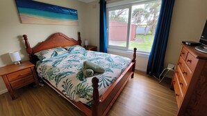 A bedroom with a wooden bed, a nightstand, a dresser, and a window with curtains. - Family friendly Smiths Beach Retreat (Smiths Beach)