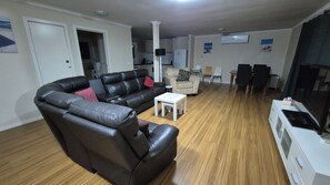 A living room with a sectional sofa, a coffee table, and a dining area with chairs.