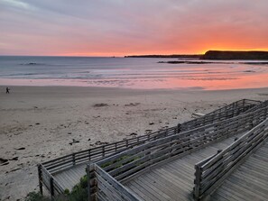 A beach with a wooden boardwalk leading to the water.