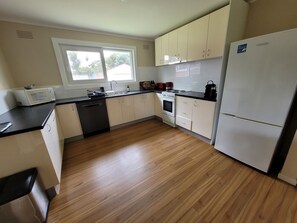 A kitchen with white cabinets, a black countertop, a dishwasher, a stove, and a refrigerator.