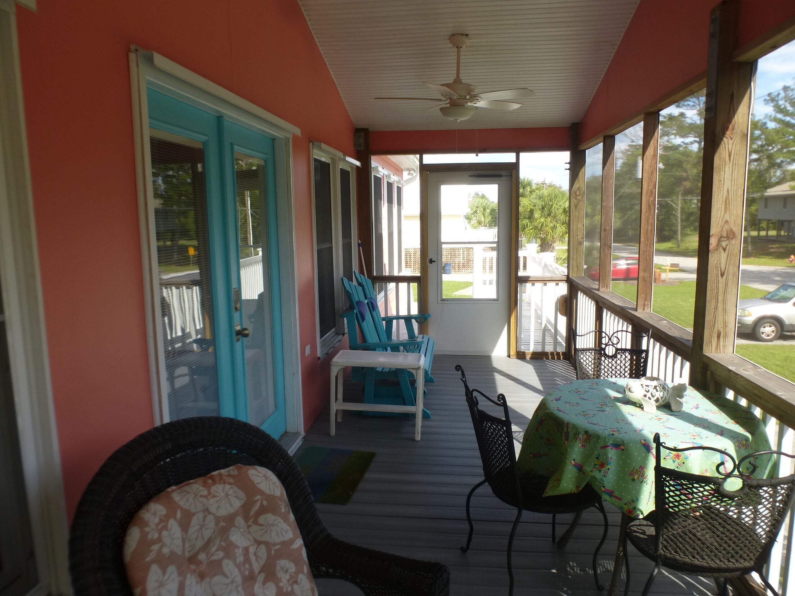 A covered porch with a table and chairs, a blue door, and a view of the street.