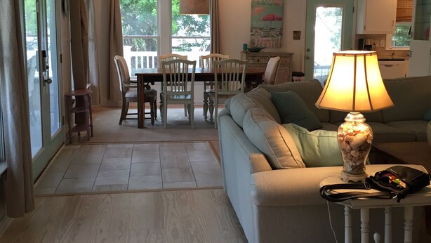 Ett rymligt vardagsrum med en soffa, ett bord med en lampa och en matplats med stolar och ett bord.