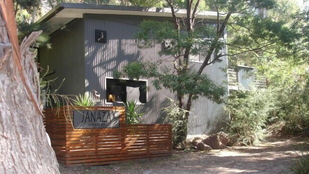 A rustic cabin with a wooden deck and a sign reading "JANAZA." - Janaza Retreat right in the middle of Halls Gap township. Pet friendly. (Halls Gap)
