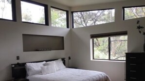 A bedroom with a bed, a nightstand, a dresser, and large windows. - Janaza Retreat right in the middle of Halls Gap township. Pet friendly. (Halls Gap)