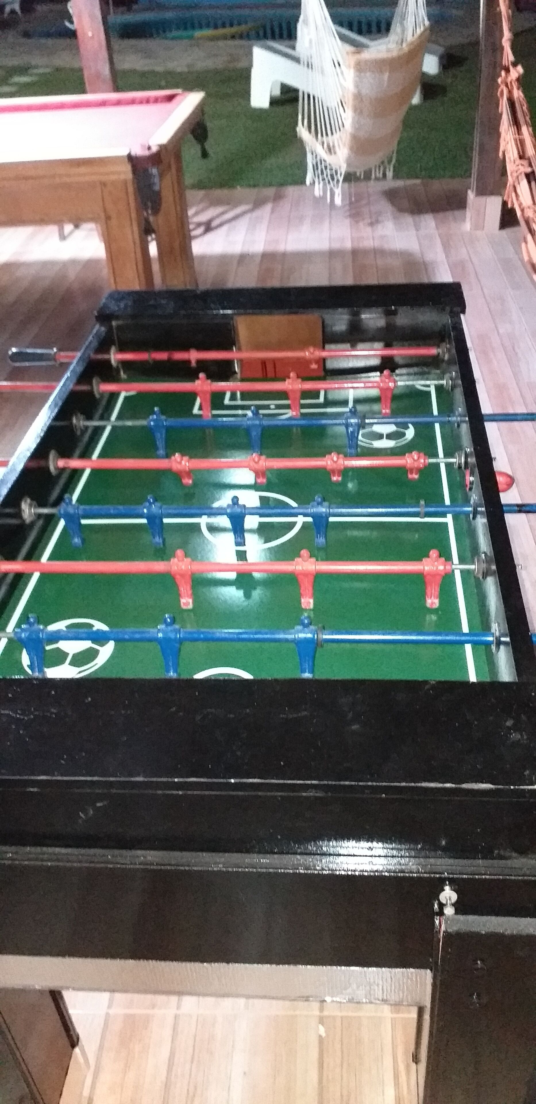Ein Kicker mit einer grünen Spielfläche und roten sowie blauen Spielfiguren.