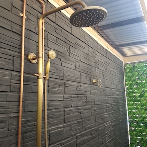 A shower with a modern design, including a rain showerhead and brass fixtures.