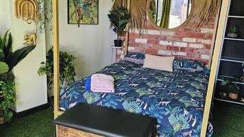 A room with a four-poster bed, a round mirror, and a brick wall.