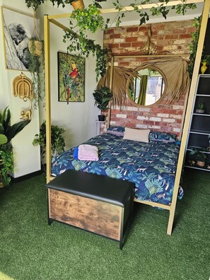 A room with a four-poster bed, a round mirror, and a brick wall.