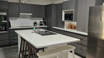 A modern kitchen with a central island, stainless steel appliances, and a skylight.