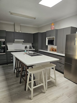 A modern kitchen with a central island, stainless steel appliances, and a skylight.