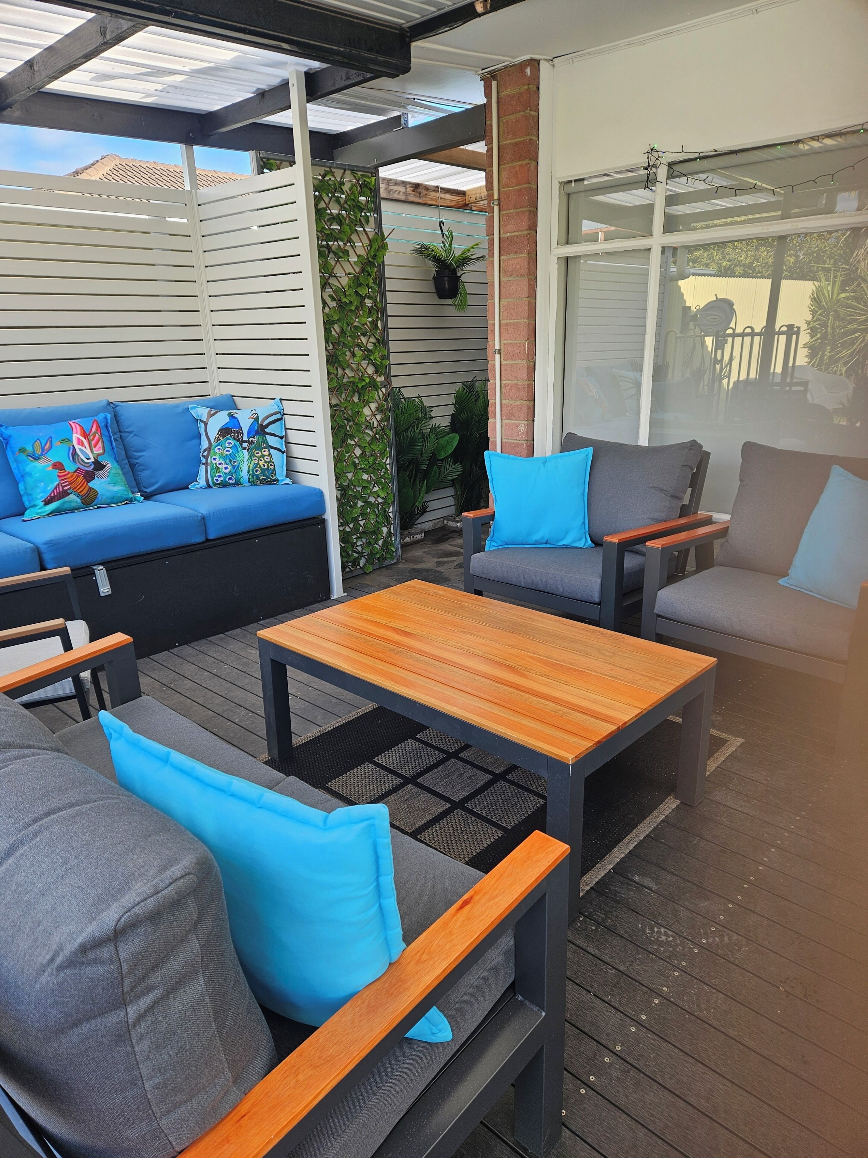 Un área de patio al aire libre con un sofá, dos sillones y una mesa de madera.