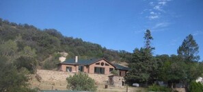 Situated on a hillside, this single-story house features a combination of brick and stucco exterior walls and a visible chimney.