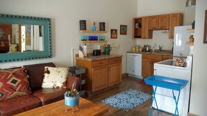 Ein kompakter Wohnraum mit Küchenzeile, einem Essbereich mit Tisch und Stühlen sowie einem Wohnbereich mit Sofa und Couchtisch.
