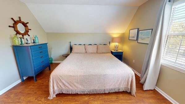 Een slaapkamer met een bed, een kast, een lamp en een raam met gordijnen.