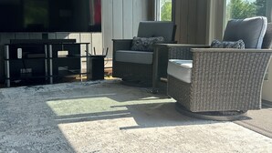 Uma sala de estar moderna com televisão de tela plana, móveis de vime e uma janela grande.