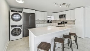 A modern kitchen with a central island, built-in appliances, and bar stools. - Suncoast Getaway – Walk to Sand & Shops (Madeira Beach)