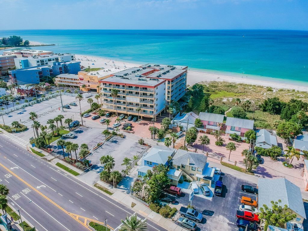 Luftaufnahme eines Küstenhotels mit Parkplatz, Zugang zum Strand und freiem Blick auf den Ozean.