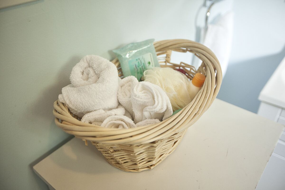 A wicker basket containing folded towels and a bar of soap on a white surface.