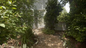 Un vialetto in giardino che conduce a un edificio con un recinto bianco e una finestra.