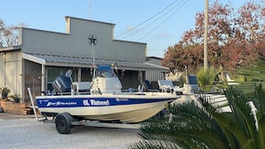 Ein Boot mit dem Namen 'OK, Whatever!' steht auf einem Kiesweg vor einem Gebäude mit einem Sternenlogo.