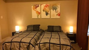 Ein Zimmer mit Doppelbett, zwei Nachttische, jeweils mit einer Lampe. Darüber hängen drei an der Wand befestigte Karten.