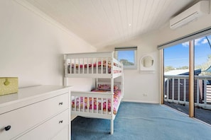 A child's room with bunk beds, a window, and a view of the outside.