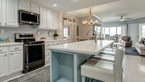 A modern kitchen with white cabinetry, a built-in oven, and a large island with seating. - Ocean View Condo | Pool, Private Beach Access, Elevator, Sleeps 8 (Tybee Island)