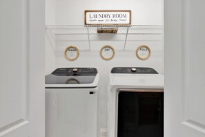 A laundry room with a sign indicating it's open 24 hours. There are three machines labeled 'WASH', 'DRY', and 'FOLD'. - Ocean View Condo on Tybee Island | Pool Access (Tybee Island)