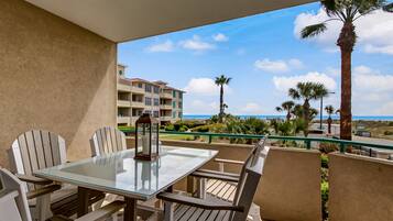 Enjoy a tranquil beachfront view from this balcony, featuring a glass-top table and comfortable seating.