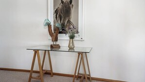A glass-top table with a wooden base, a vase with flowers, and a framed picture of a horse on the wall. - Uninterrupted Views Encounter Bay (Encounter Bay)