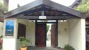A building entrance with a sign reading "1586" and a poster titled "Ilhas do Jucely". - Juquehy, beachfront, almost on the sand, special offer February/26, 6 people. (São Sebastião)
