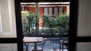 An open door leading to a patio with a table and chairs, a small rug, and a pair of shoes on the floor. - Juquehy, beachfront, almost on the sand, special offer February/26, 6 people. (São Sebastião)