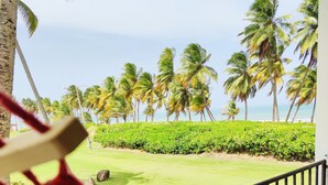 A hammock on a balcony overlooking a grassy area with palm trees and a view of the ocean. - Beach Front & 3 levels & Terrace & Balcony & 2 Pools Max 6people (Río Grande)
