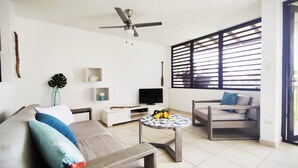 A modern living room with a sofa, a coffee table, a TV, and a ceiling fan. - Beach Front & 3 levels & Terrace & Balcony & 2 Pools Max 6people (Río Grande)
